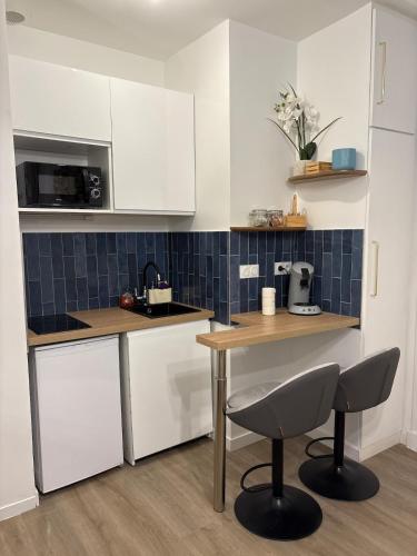 une cuisine avec des armoires blanches et une table et des chaises dans l'établissement Appartement Saint-Pierre TOULOUSE hyper centre ville, à Toulouse