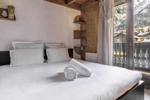 une chambre avec un grand lit blanc avec une fenêtre dans l'établissement Les Arolles - Duplex familial - Vue montagne, aux Houches