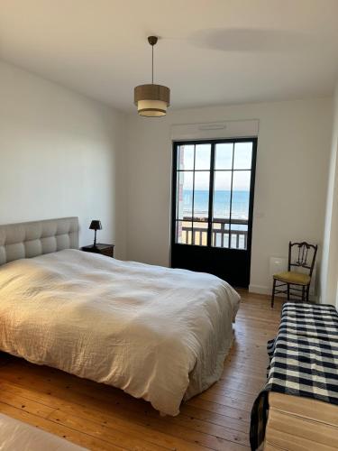 une chambre avec un grand lit et une grande fenêtre dans l'établissement Maison d'exception face à la mer, à Saint-Aubin-sur-Mer