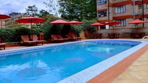 ein Swimmingpool mit Stühlen und Sonnenschirmen neben einem Gebäude in der Unterkunft Lantana Suites in Nairobi