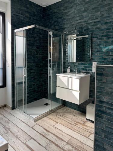 une salle de bain avec une douche en verre et un lavabo dans l'établissement Maison d'exception face à la mer, à Saint-Aubin-sur-Mer