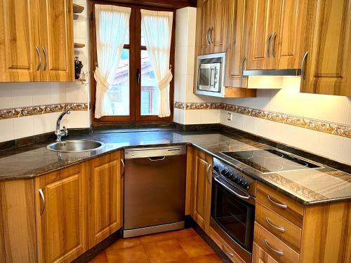 a kitchen with wooden cabinets and a sink at Viviendas Rurales El Cantón in Cucayo