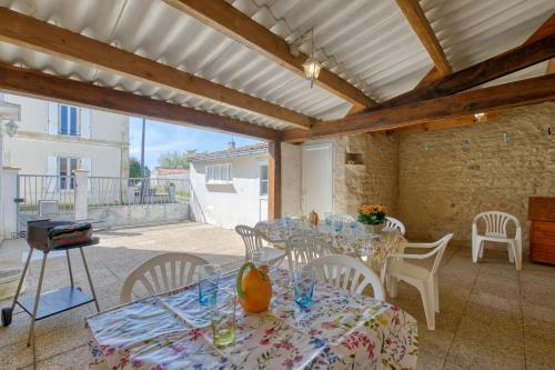 un patio avec des tables, des chaises et un grill dans l'établissement MAISON AU CŒUR DU VILLAGE, à Saint-Nazaire-sur-Charente