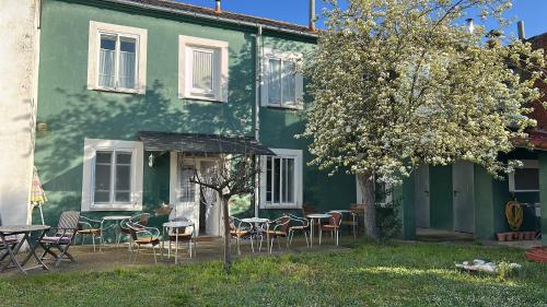 a green house with tables and chairs in front of it at La Casa Verde Albergue - Solo Peregrinos in San Martín del Camino