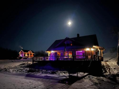 a house lit up with lights in the snow at night at Päikseranna Puhkemaja in Rõssa