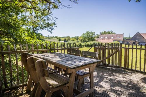 une table et des chaises en bois sur une terrasse avec une clôture dans l'établissement Boomhuis Domaine Bonneblond, à Saint-Désiré