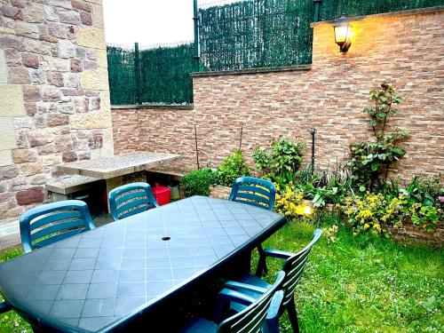 a table and chairs in a backyard with a brick wall at Viviendas Rurales El Cantón in Cucayo
