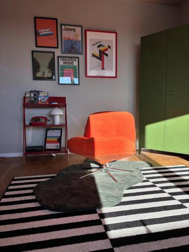 a living room with an orange chair and a rug at Yellow Lotus in Gdańsk