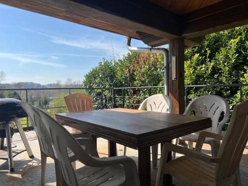 une table et des chaises en bois sur un porche avec vue dans l'établissement Le Jonquet maison 12 pers Sauna Jacuzzi, à Douriez