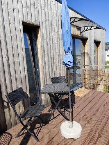 a table and chairs on a deck with a blue umbrella at Little Tiny Village Haus 4 in Fußach