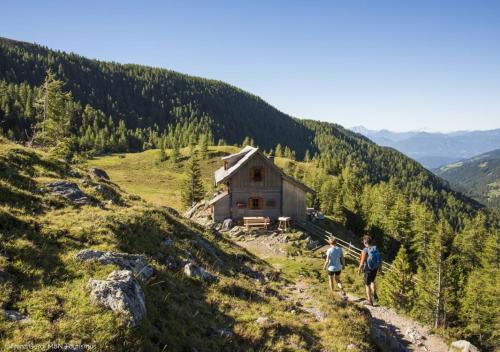 two people walking up a hill near a cabin at Chalet Bergblick Suites - Luxury Escape in Bad Kleinkirchheim