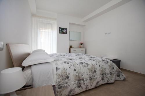 a white bedroom with a bed with a floral blanket at Case vacanze Taiji in Cassino