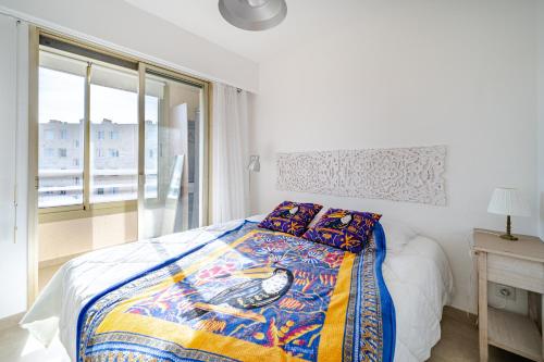 une chambre avec un lit avec une couette et une fenêtre dans l'établissement 2 pièces Calme Proche de la mer Parking en sous-sol, à Cagnes-sur-Mer