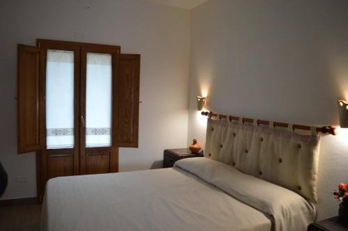 Un dormitorio con una cama blanca y dos ventanas. en Agriturismo S'Orgiola, en Cardedu