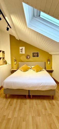 a bedroom with a large white bed with a skylight at Gîte Havre forêt in Bouillon