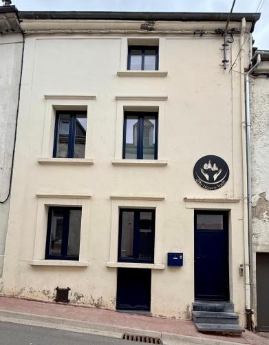 a white building with a blue door on a street at Gîte Havre forêt in Bouillon