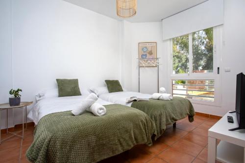 a bedroom with two beds with green blankets and a window at Sunstay Chalet La Colina Torremolinos in Torremolinos