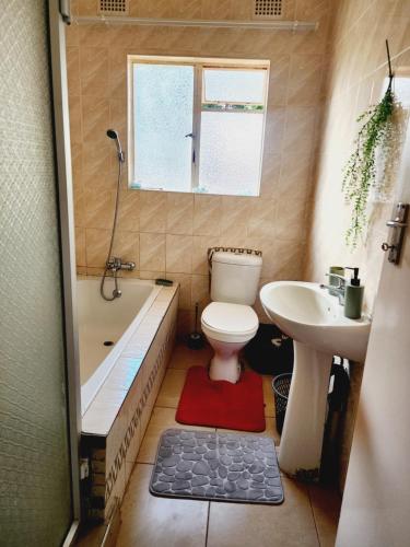 a bathroom with a toilet and a tub and a sink at Eastern Road Executive Suites in Harare