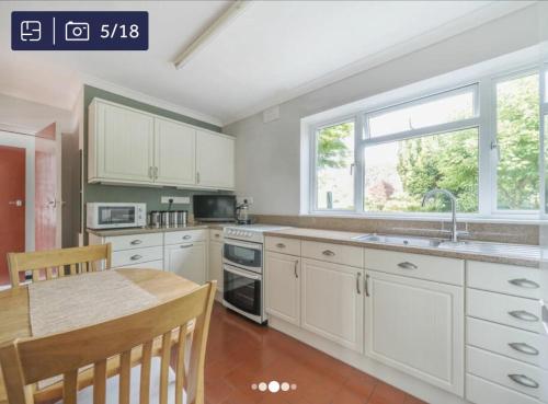 a kitchen with white cabinets and a table and a window at Archtrees House - Family home in Surrey village in Lingfield