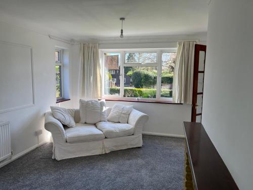 a living room with a white couch and a window at Archtrees House - Family home in Surrey village in Lingfield