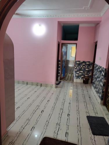 an empty room with pink walls and a tile floor at Jamenas house in kolkata