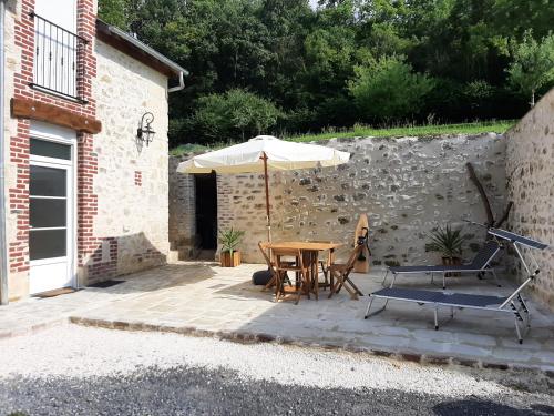 a patio with an umbrella and a table and chairs at La Grange des Richebourgs in Vauxaillon