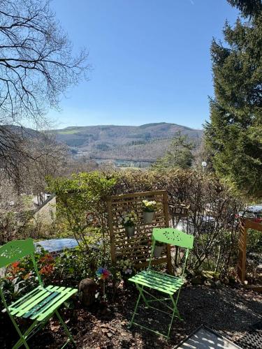 two green chairs sitting in a garden with mountains in the background at Vieux Sart 34, chez Dame Béa in Stavelot