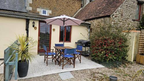a patio with a table and chairs and an umbrella at The Lions Den - La Loge Guest House in Mantilly