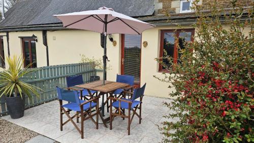 a table and chairs with an umbrella on a patio at The Lions Den - La Loge Guest House in Mantilly
