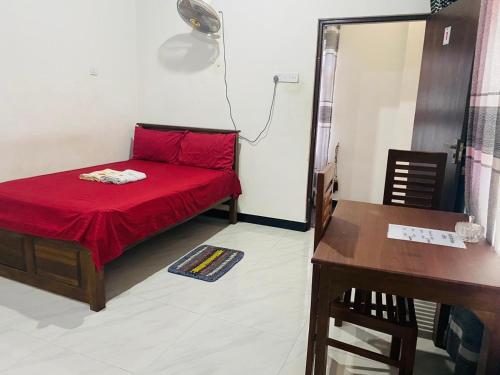a small room with a red bed and a desk at Black Rose Guest in Gampaha