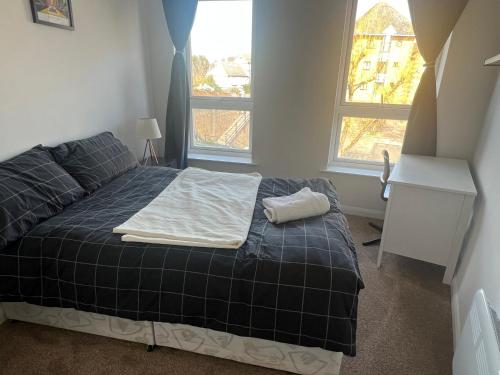 a bedroom with a bed with a blue blanket and two windows at Cosy double room in Canada Water in London
