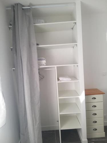 a closet with white shelves and a curtain at Appartement privé moderne et lumineux plain-pied in Oyonnax