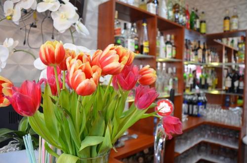 een vaas gevuld met rode en roze bloemen in een bar bij Zajazd U Renaty in Poraj