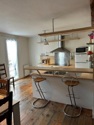 une cuisine avec un comptoir et des tabourets. dans l'établissement Maison triplex centre de Lourdes, à Lourdes