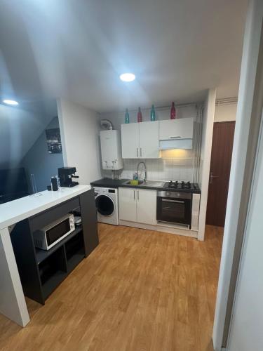 une cuisine avec des armoires blanches et un plancher en bois dans l'établissement Appartement, à Charleville-Mézières