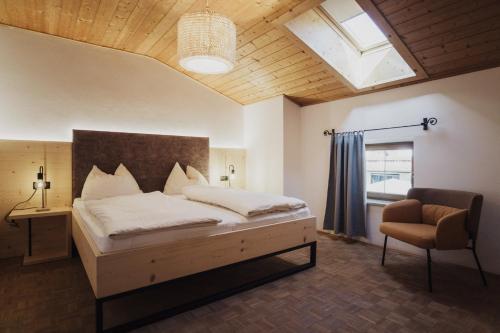 a bedroom with a bed and a chair and a window at Töllhof STUDIO mit BAUERNSTUBE in Bressanone