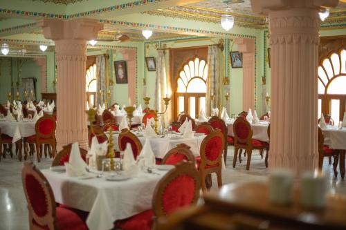 プシュカルにあるUmaid Mahal Palaceのダイニングルーム(白いテーブル、赤い椅子付)