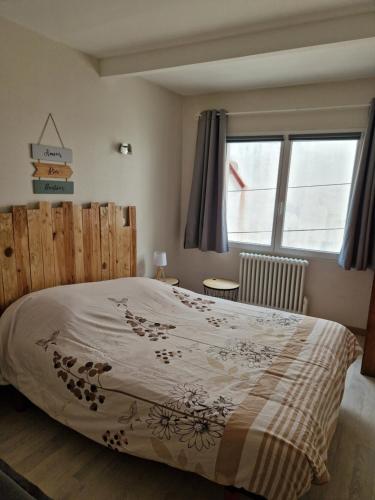 une chambre avec un lit avec une tête de lit en bois et une fenêtre dans l'établissement Petite maison au cœur du village, à Cessenon