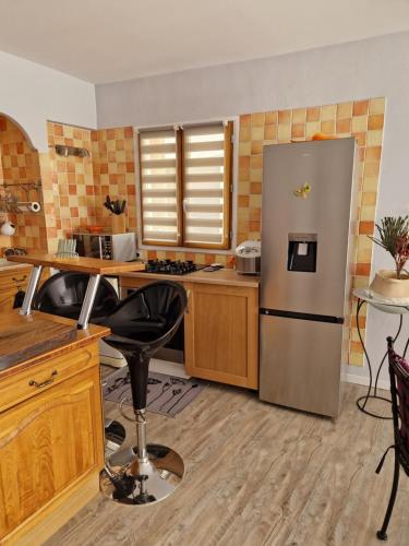 une cuisine avec un réfrigérateur en acier inoxydable et des armoires en bois dans l'établissement Petite maison au cœur du village, à Cessenon