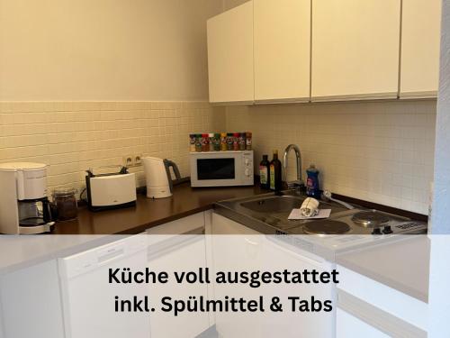 un comptoir de cuisine avec un évier et un micro-ondes dans l'établissement FeWo Berg-Domizil Altenau inklusive Bettwäsche und Handtüchern, à Altenau