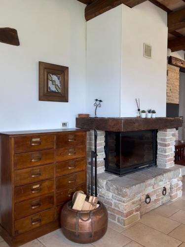 a living room with a fireplace and a wooden dresser at Villa Altrove in Montemarciano