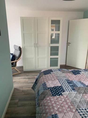 a bedroom with a bed and white cabinets and a chair at Linke Ferienwohnung im Ferienhaus Seestern in 06249 Mücheln in Büchel
