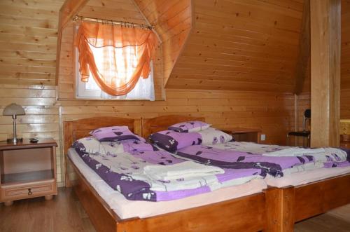 a bedroom with a large bed in a wooden cabin at Zajazd U Renaty in Poraj