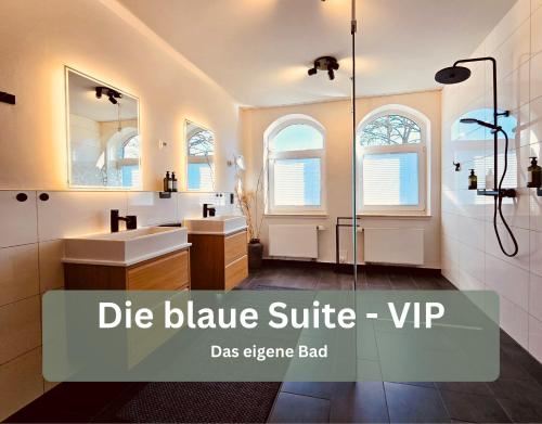 a bathroom with two sinks and a glass shower backdoor at Lounge94 - Luxus auf 180 m2 in Wilhelmshaven