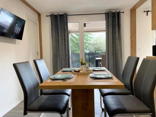 a dining room table with black chairs and a window at Mobilna kućica Neda - Grebaštica, kamp Vala in Grebaštica