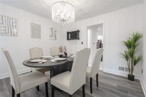 a dining room with a black table and white chairs at Big Modern Family Home On 1 Acre Land w Firepit & Grill in Ellenwood