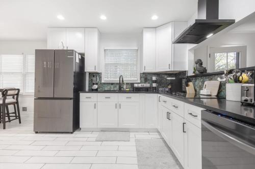 a kitchen with white cabinets and a stainless steel refrigerator at Big Modern Family Home On 1 Acre Land w Firepit & Grill in Ellenwood
