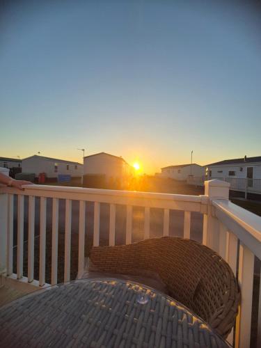 a bench on a balcony with the sunset in the background at Jan' Sea View Getaway in Heysham