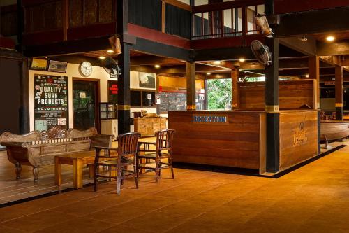a restaurant with a bar with chairs and a table at Plengkung Lodge G-Land in Ringinpintu