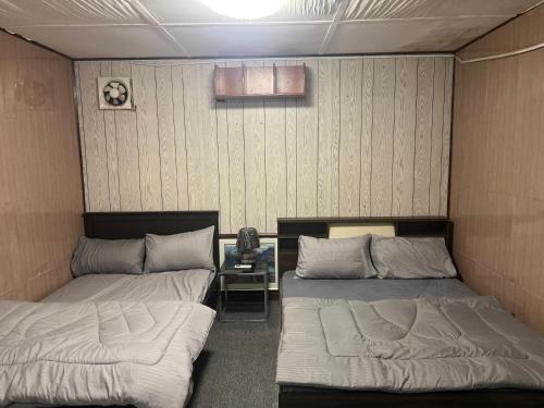 a room with two beds and a table at Shinas Farm in Al Hāmilīyah